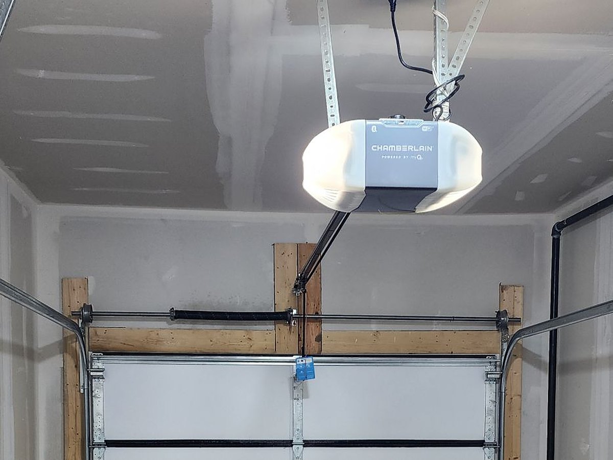 Opener mounted to a finished garage ceiling with the rail running forward to the door arm at the top section